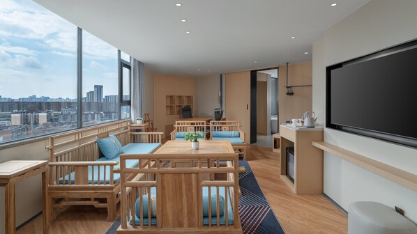 A modern living room with a large window, wooden furniture, and a flat-screen TV. - Holiday Inn Express Kunming Railway Station by IHG (Kunming)