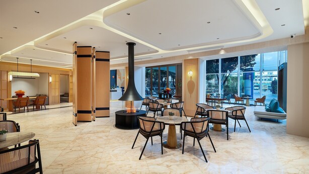 A spacious lobby with a central seating area, a large fireplace, and a view of the outdoors through large windows. - Holiday Inn Express Kunming Railway Station by IHG (Kunming)