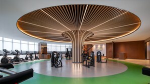 Un gimnasio moderno con un diseño de techo original, diverso equipo de ejercicio y suelo verde.