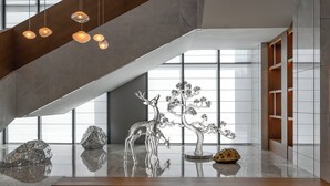Un interior moderno con una escalera, lámparas colgantes y un suelo reflectante.