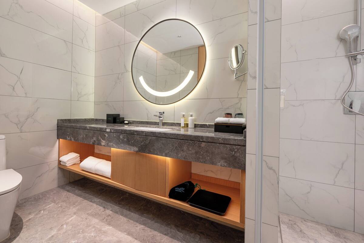 Une salle de bain moderne avec un sol en marbre, des toilettes, un lavabo avec un miroir et une douche.