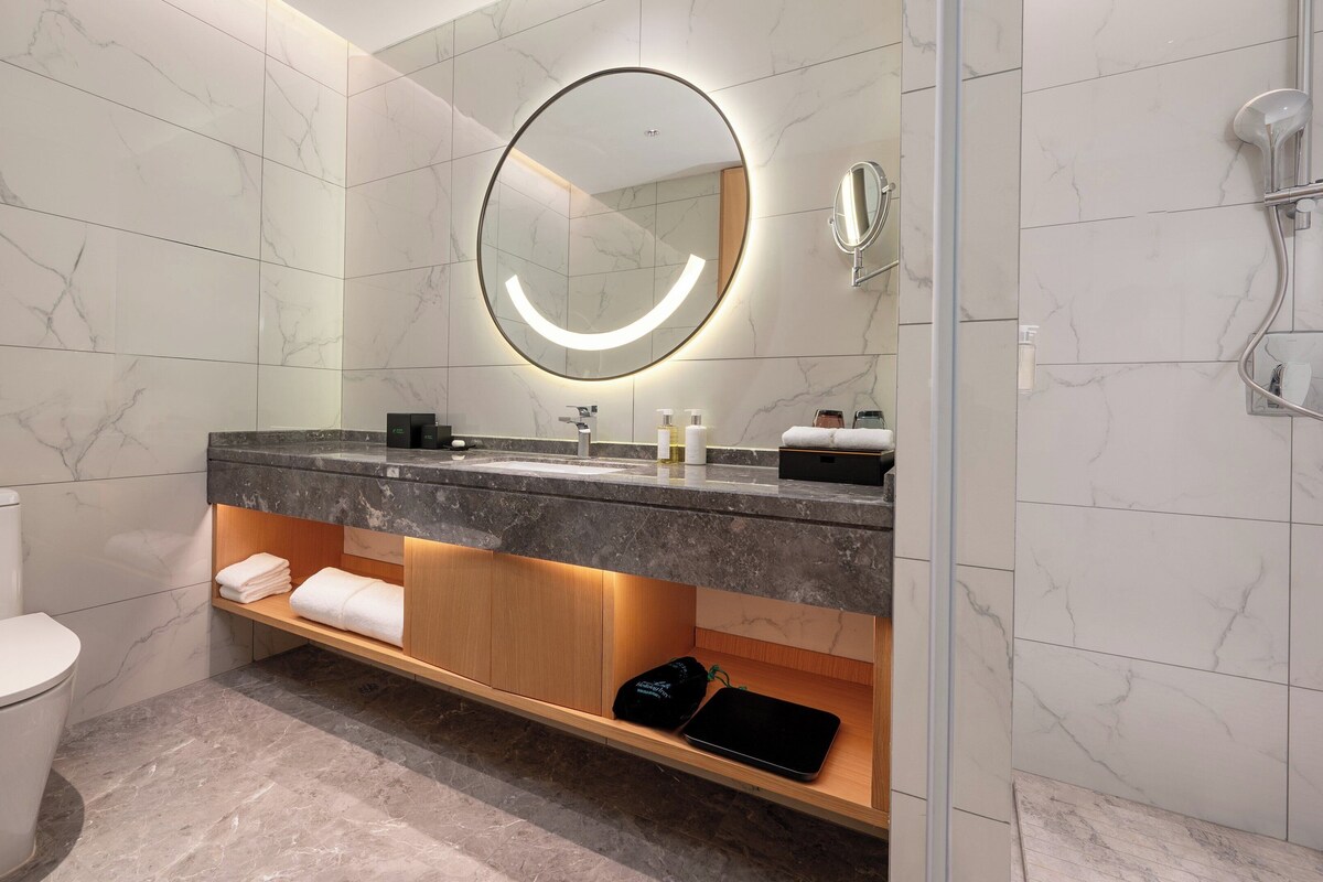 Une salle de bain moderne avec un sol en marbre, des toilettes, un lavabo avec un miroir et une douche.