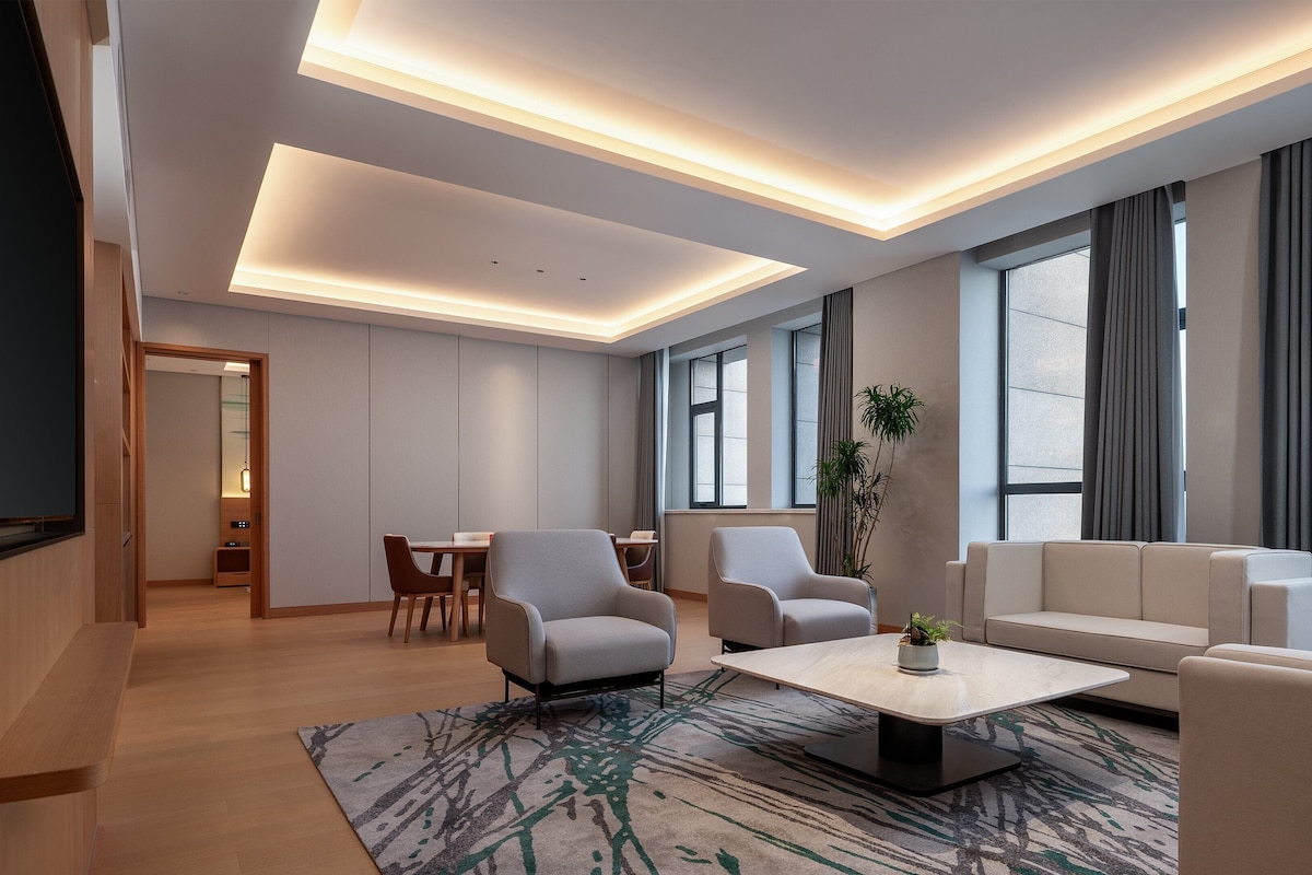 Una sala de estar moderna con un sofá, sillones, una mesa de centro y un comedor con mesa y sillas.