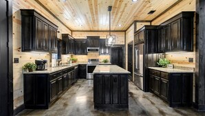 A modern kitchen with dark cabinetry, a central island, and a wooden ceiling. - Hot Tub · Detached Game Rm · Pool Table | Dogs OK (Broken Bow)