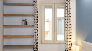 A room with a window, wooden shelves, a bedside lamp, and a bed. - Rental in Rome Roma Campus Martius Apartment (Rome)