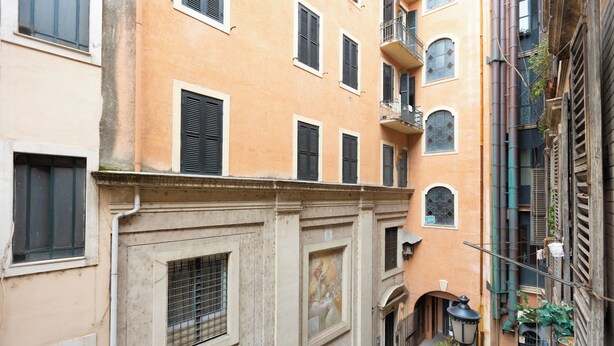 A narrow street with buildings featuring balconies and shutters. - Rental in Rome Roma Campus Martius Apartment (Rome)