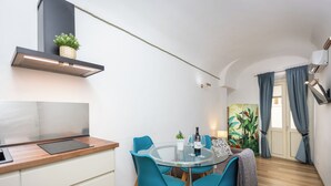 A modern kitchen with a glass dining table, teal chairs, and a wooden countertop. - Rental in Rome Roma Campus Martius Apartment (Rome)