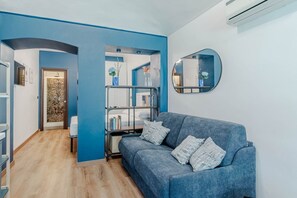 Un salon moderne avec un canapé bleu, une bibliothèque et un miroir.