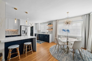 Una cocina moderna con armarios blancos, un refrigerador de acero inoxidable y una isla central con taburetes.