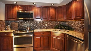 Una cocina con gabinetes de madera, electrodomésticos de acero inoxidable y salpicadero de azulejos.