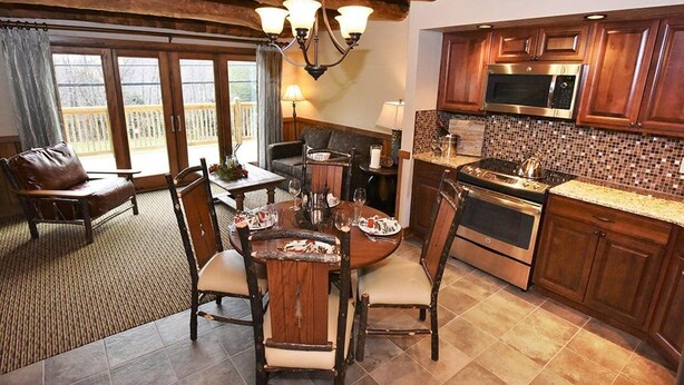 A spacious kitchen with wooden cabinets, a large stove, and a dining area with a table set for four. - Charming Chalet Escape | Ski-In Fun + Private Deck (Champion)
