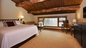 Un dormitorio con techo de madera, una cama, un escritorio y un aparador.