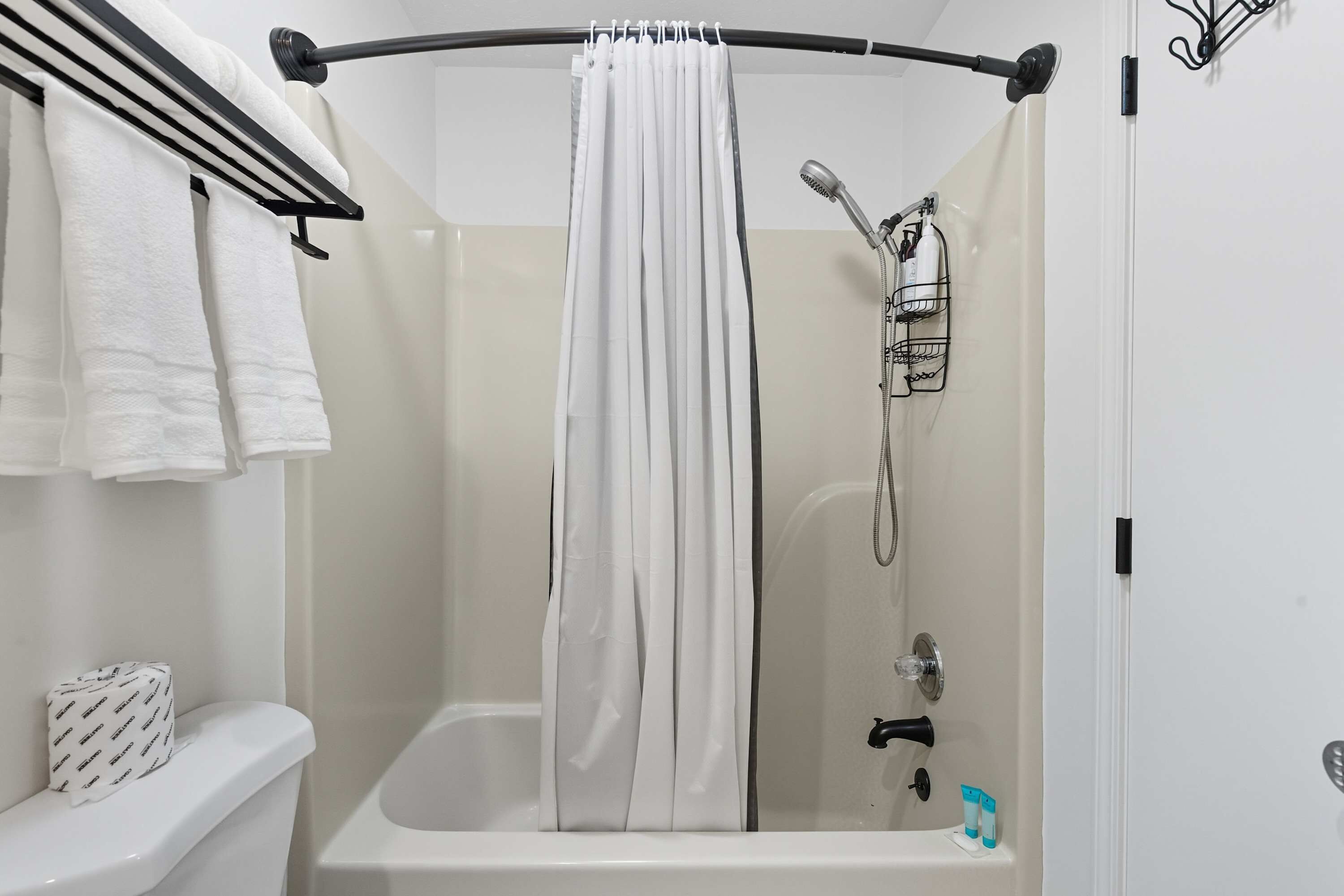 Un espace douche équipé d’un rideau, d’un porte-serviettes et d’un pommeau de douche.