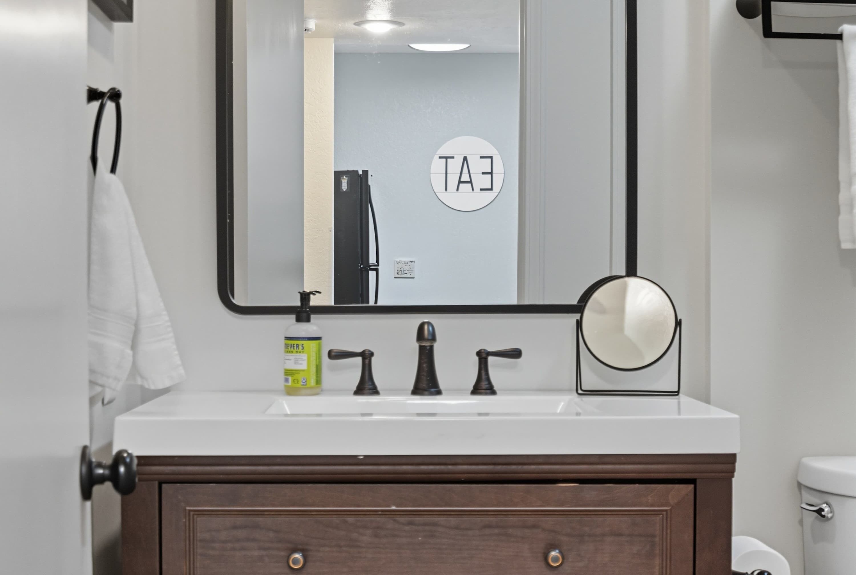 A bathroom with a white sink, a mirror, and a toilet.