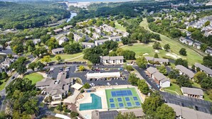 Una vista aerea di una zona residenziale con case, un campo da tennis e un campo da golf.