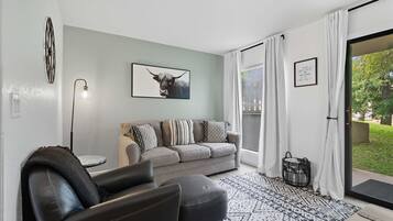A modern living room with a grey sofa, black leather armchair, and a patterned rug.