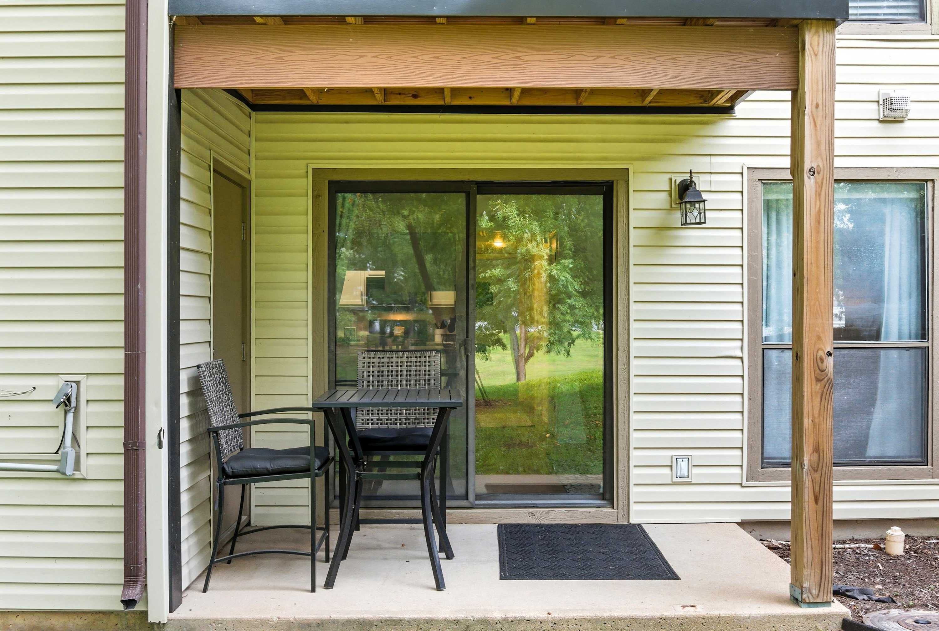 A covered porch with a table and chairs, a sliding glass door, and a wooden post.