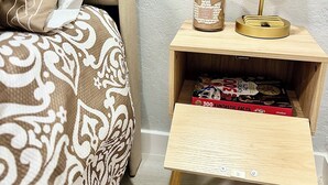 Een netjes ingerichte slaapkamer met een bed, nachtkastje, lamp en een klein houten nachtkastje met een boek.