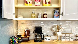 Een keuken met witte kasten, een koffiebar en een plank met popcorn en dozen Orville Redenbacher's popcorn.