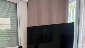 Un escritorio moderno con una pantalla plana grande, una cafetera roja y una silla blanca.