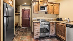 Una cocina con armarios de madera, un refrigerador de acero inoxidable, un microondas, una estufa y un lavavajillas.