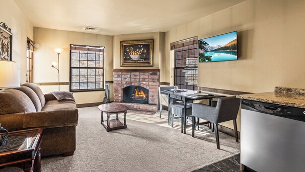 A living room with a fireplace, a dining area, and a kitchen with a dishwasher.