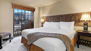 A hotel room with a large bed, a bench, a window with a view, and a nightstand with a lamp. - 1 block from Park City Mountain with hot tub Managed by Park City Lodging (Park City)