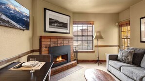 A living room with a fireplace, a sofa, a dining table with a glass, and a lamp.
