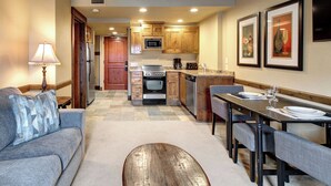 A modern kitchen with wooden cabinets, a microwave, oven, and a dining area with a table set for two.
