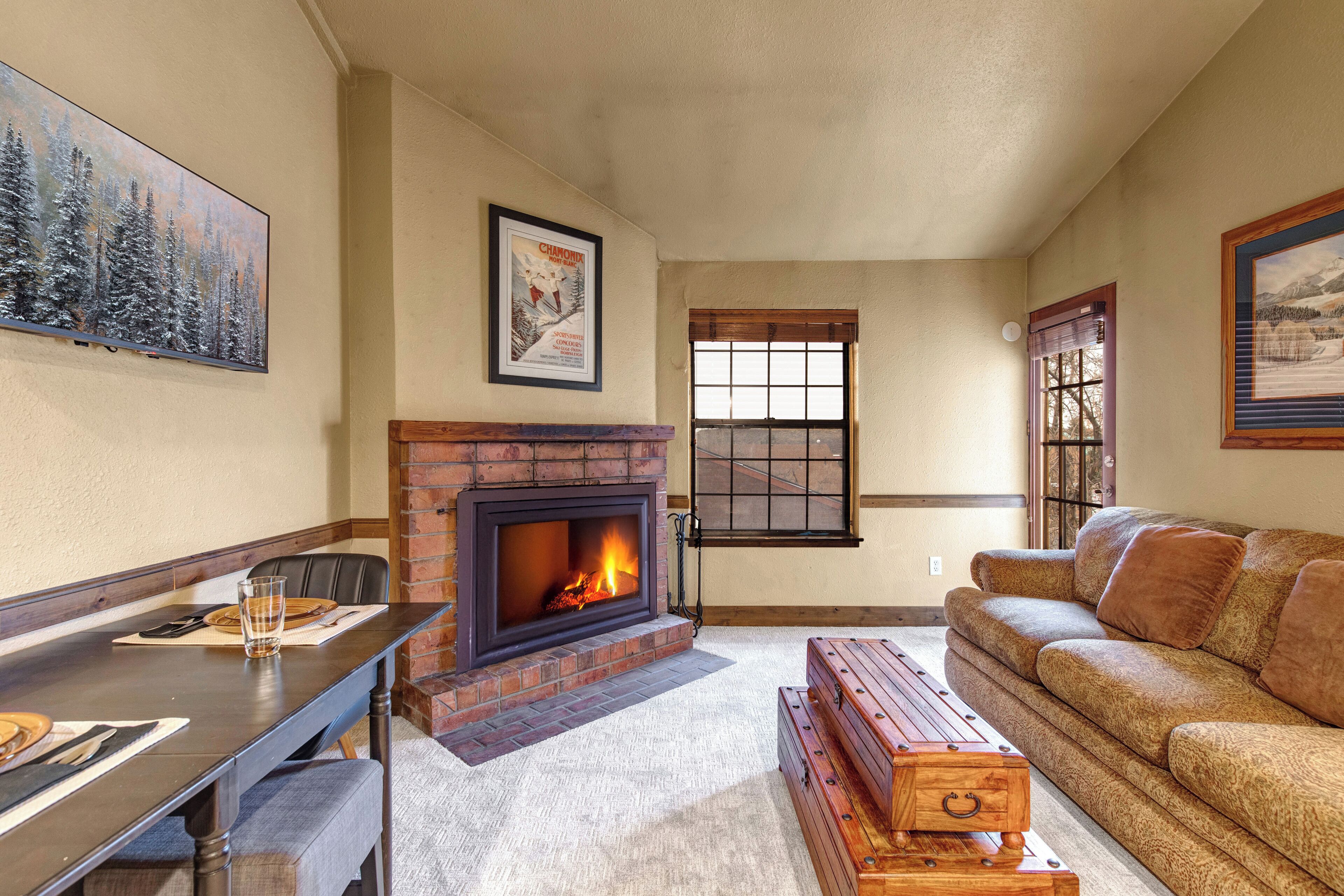 Una sala de estar acogedora con chimenea, una mesa de comedor y un sofá.