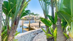 A pathway leading to a dock area with palm trees and a clear view of the water. - Ibis Island Escape (Fort Myers Beach)