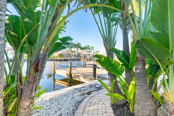 A pathway leading to a dock area with palm trees and a clear view of the water.