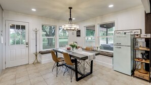 Eine geräumige Küche mit Esstisch, Stühlen, einer Chandelier und einem Kühlschrank.
