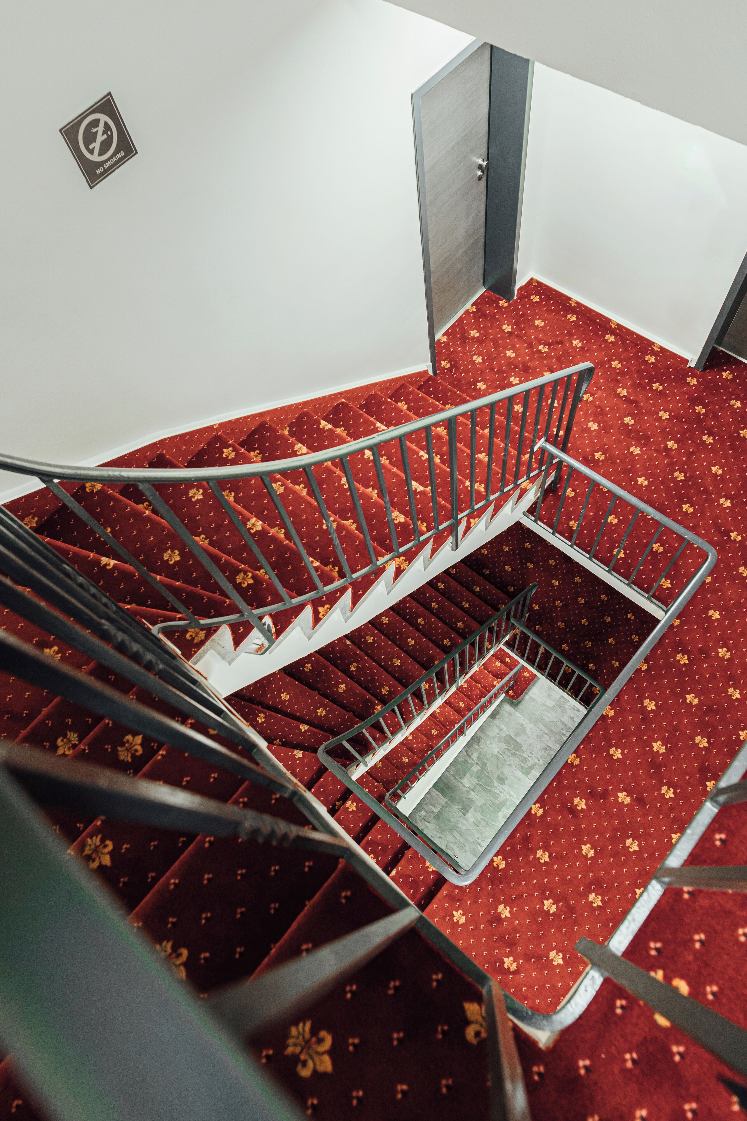 A staircase with red carpet and metal railings leading to an upper floor.