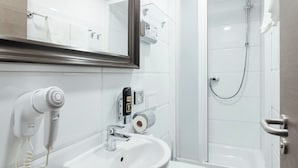 A bathroom with a white sink, a hairdryer, a toilet, and a shower.