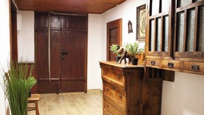 A hallway with a wooden door, a wooden dresser with drawers, a small table with a potted plant, and a tiled floor. - Holiday cottage surrounded by vineyards (Zgornji Leskovec)