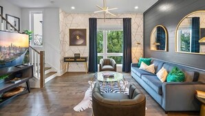 A modern living room with a sofa, armchairs, a coffee table, and a TV. - Upscale & Cool - Walk to Bars - Mins. to Broadway (Nashville)