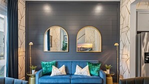A modern living room with a dark blue sofa, two gold-framed mirrors, and decorative pillows. - Upscale & Cool - Walk to Bars - Mins. to Broadway (Nashville)
