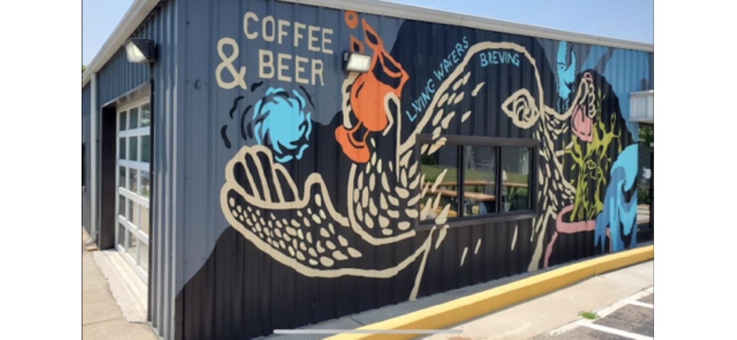En byggnad med en väggmålning som visar reklam för kaffe och öl, och orden ”Living Waters Breving” på sidan.