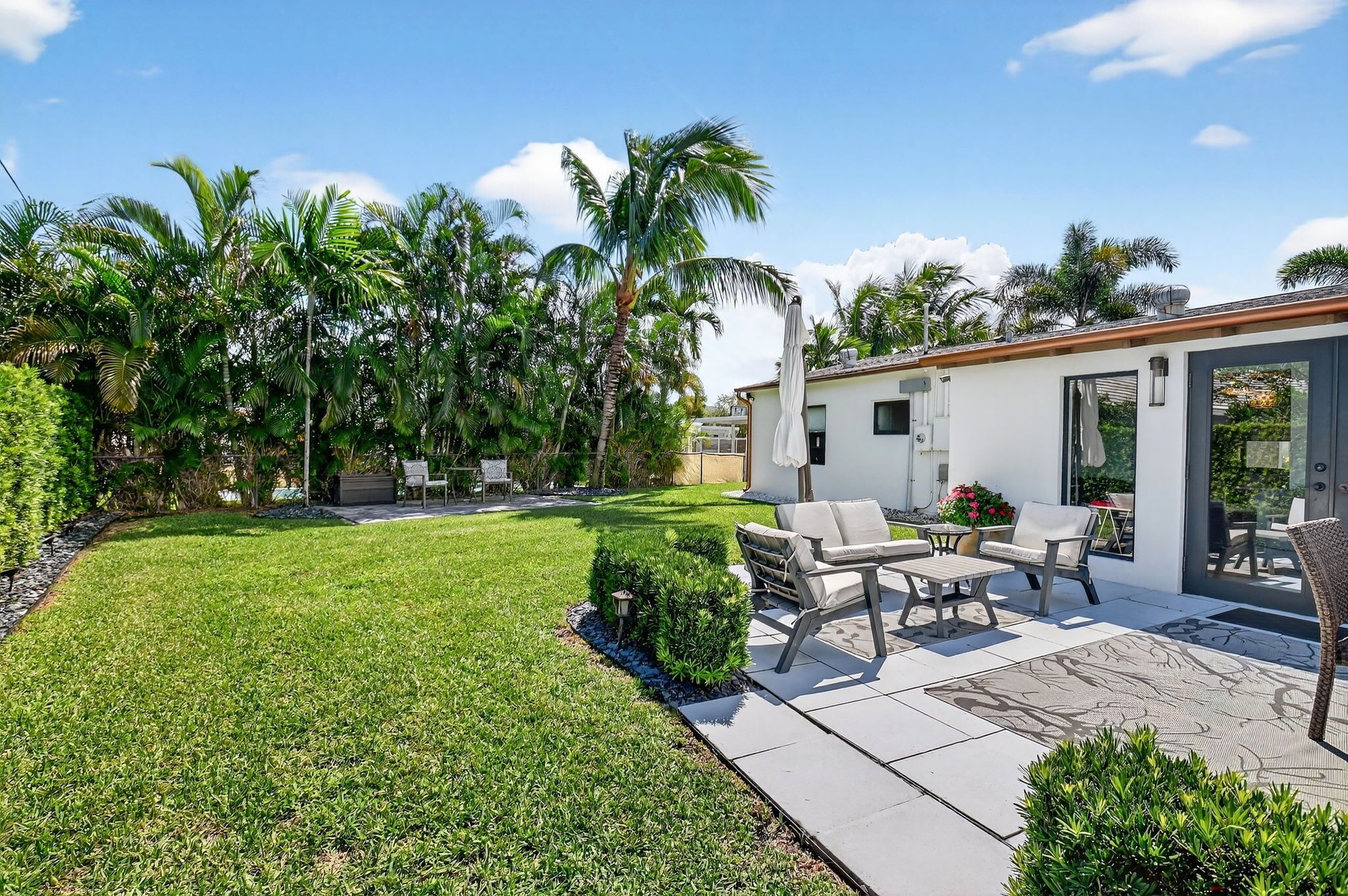A modern outdoor patio with a seating area, a small pool, and lush tropical vegetation.