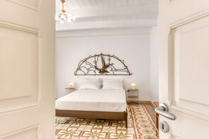 A bedroom with a bed, a decorative wall piece, two bedside tables, and a patterned floor.