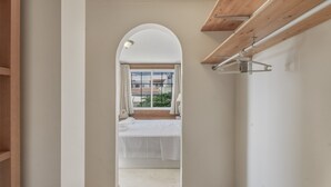A hallway leading to a bedroom with a large window, wooden ceiling beams, and a bed with white bedding. - Vacation Villa 'La Caleta Seaside  with Pool' with Sea View, Wi-Fi and Air Conditioning (Adeje)