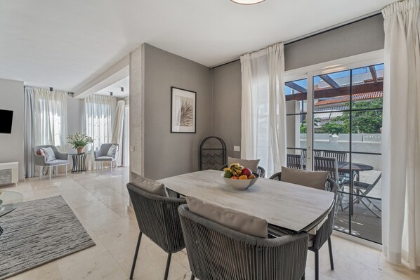 A modern dining area with a table, chairs, and a fruit bowl.