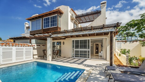 A two-story building with a swimming pool, outdoor seating, and a covered patio area. - Vacation Villa 'La Caleta Seaside  with Pool' with Sea View, Wi-Fi and Air Conditioning (Adeje)