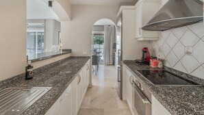 A modern kitchen with granite countertops, stainless steel appliances, and a view into the dining area. - Vacation Villa 'La Caleta Seaside  with Pool' with Sea View, Wi-Fi and Air Conditioning (Adeje)