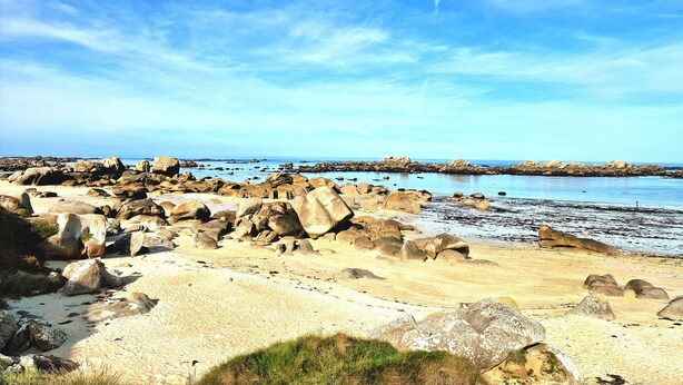 A rocky beach with large boulders and a clear sky.
