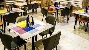 Un restaurant doté de nombreuses tables et chaises, de climatiseurs et d’un sol carrelé.