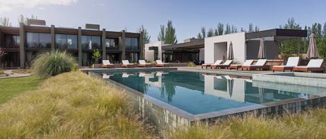 A modern pool area with lounge chairs and a building with large windows.
