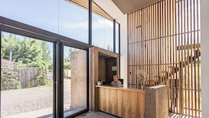A reception area with a wooden desk, large windows, and a view of the outdoors. - Vistalba Hotel  Aparts & Suites (Luján de Cuyo)