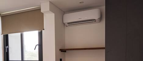 Une chambre à coucher comprenant un lit, une fenêtre avec un store, une étagère intégrée et une armoire.